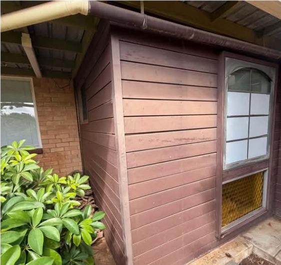 Before: tired dark-stained timber cladding on the side of a house, weathered and faded.