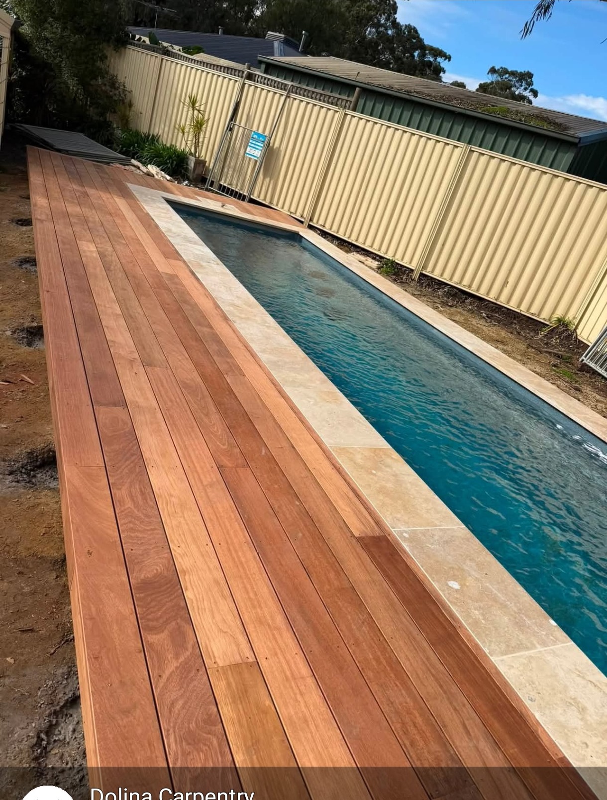 Newly laid hardwood timber pool deck running the length of a lap pool in a backyard.
